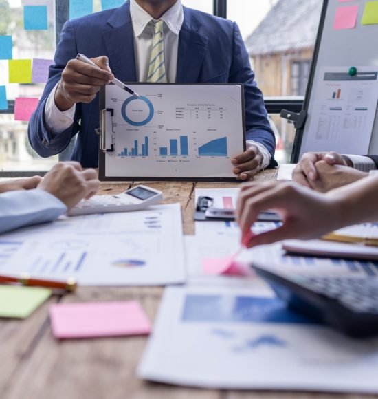 Group of confident business people point to graphs and charts to analyze market data, balance sheet, account, net profit to plan new sales strategies to increase production capacity.